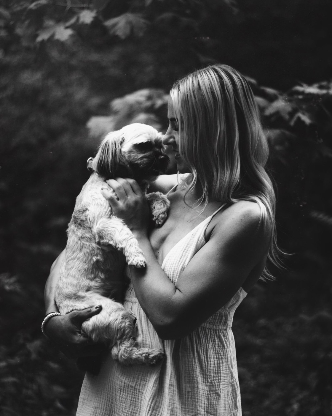 Black and white photo of a woman nuzzling a small dog